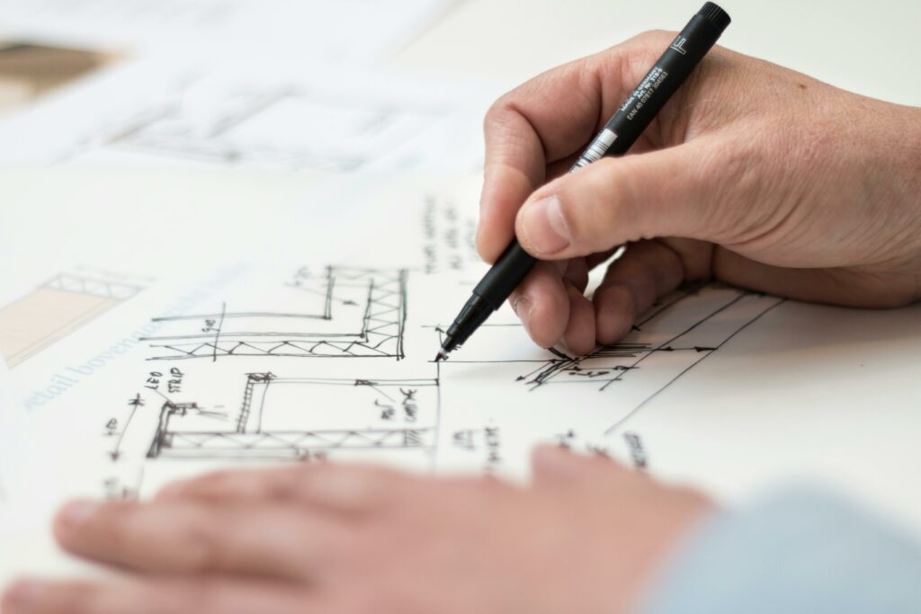 pexels-photo-1109541-1109541 Close-up of hand drawing intricate technical designs on blueprint with pen, ideal for engineering or architecture themes.